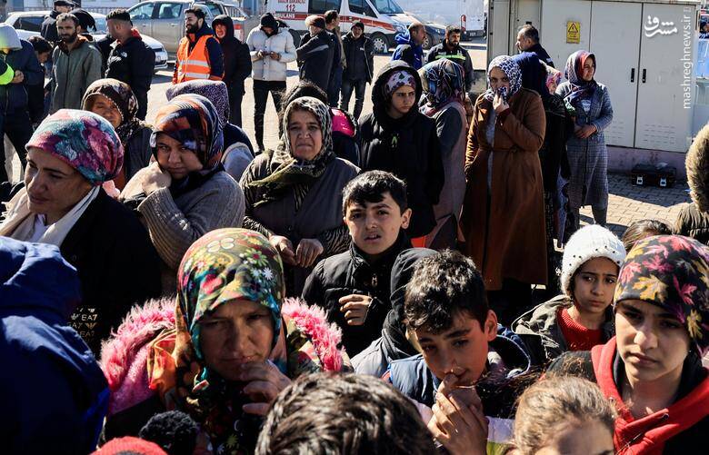 افراد آواره منتظر دریافت غذا در یک پیست ورزشی که به عنوان اردوگاه بازماندگان زلزله در آدیامان، ترکیه خدمت رسانی می کند.