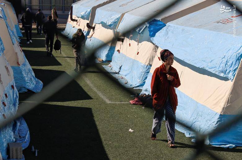 مردم در یک پیست ورزشی که به عنوان اردوگاه برای بازماندگان زلزله در آدیامان، ترکیه خدمت رسانی می کند، به تصویر کشیده شده است.