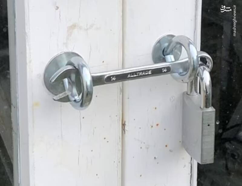 شخصی از قفل و آچار برای محکم کردن دو دَر در کنار هم استفاده میکند.