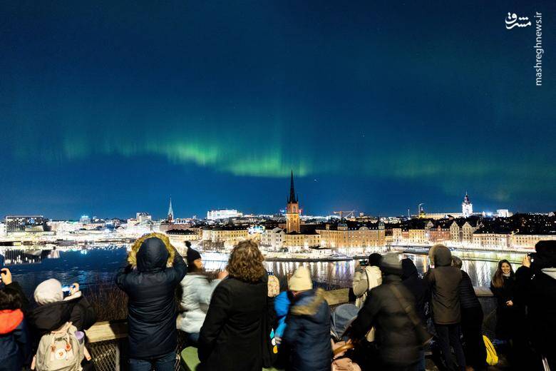 مردم به تماشای شفق قطبی در آسمان نشسته اند./ استکهلم - سوئد