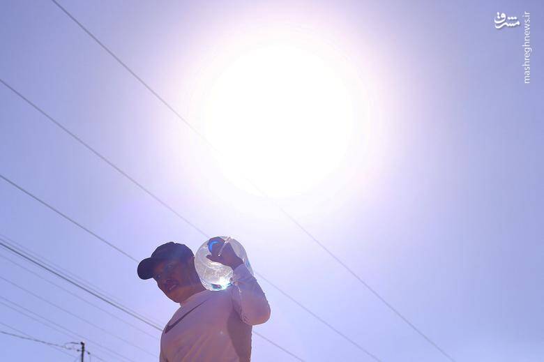 مردی ظرفی پر از آب را در دمای بالای هوا در سیوداد خوارز مکزیک حمل می‌کند.