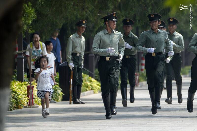 ژست بامزه یک دختر بچه در کنار اعضای گارد افتخاری در یک روز گرم پکن _ چین