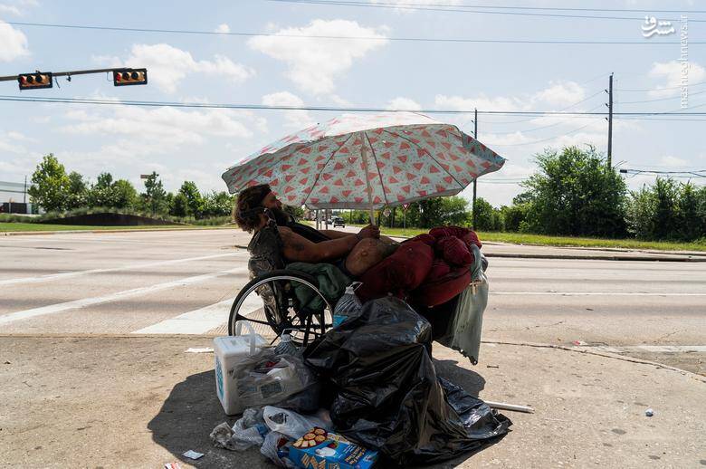 یک بی خانمان برای در امان ماندن از نور خورشید چتری مقابل خود قرار داده است./ تگزاس _ آمریکا