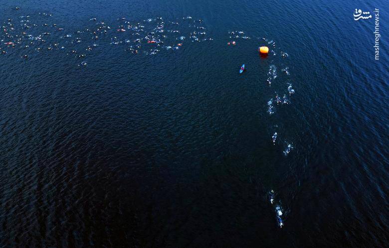 شرکت کنندگان در طول مسابقات سه گانه در دریاچه ویندرمر _ بریتانیا شنا می‌کنند.