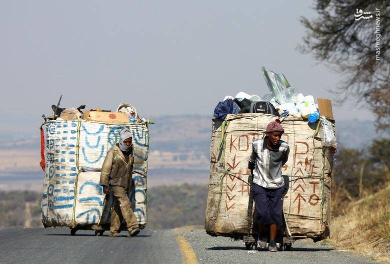 استیون لسونا و تابانگ پوله دو جمع کننده زباله چرخ دستی‌های پر از مواد قابل بازیافت را می‌کشند./ ژوهانسبورگ _ آفریقای جنوبی