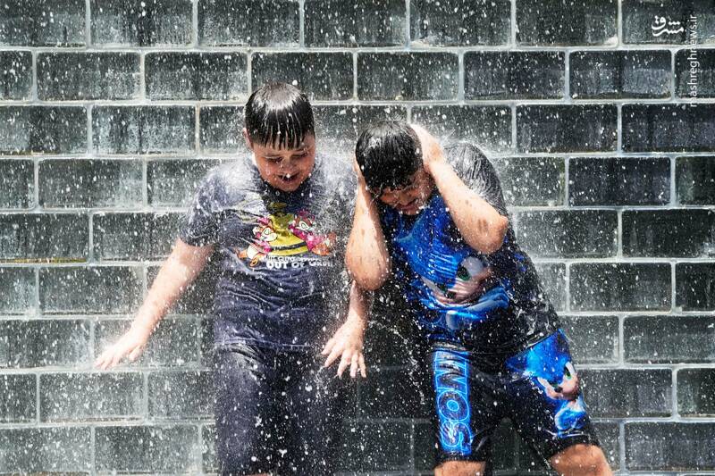 دو کودک از شدت گرما در فواره کراون در پارک هزاره در شیکاگو بازی می‌کنند