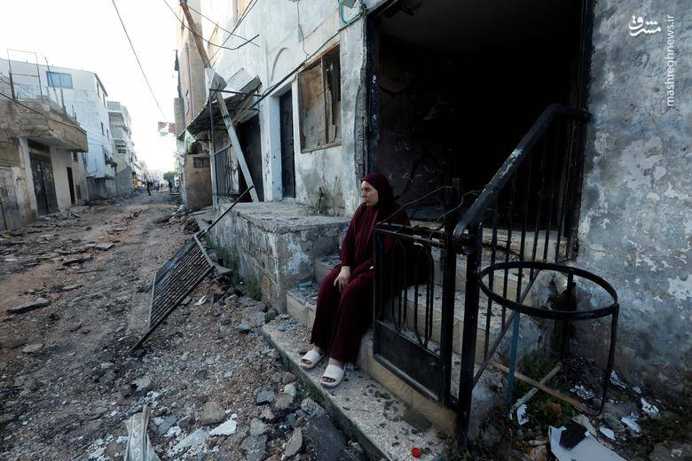 یک زن فلسطینی پس از عقب نشینی ارتش رژیم صهیونیستی از اردوگاه جنین در کرانه باختری مقابل یک ساختمان آسیب دیده نشسته است.