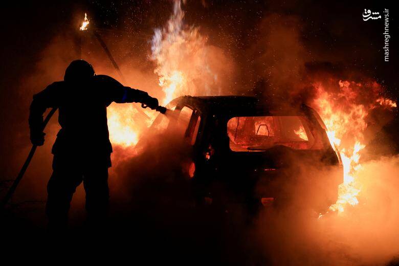تلاش یک آتش نشان برای خاموش کردن خودرو در حال سوختن در حاشیه درگیری پلیس با معترضان به کشته شدن نوجوان 17 ساله به دست پلیس در پاریس _ فرانسه
