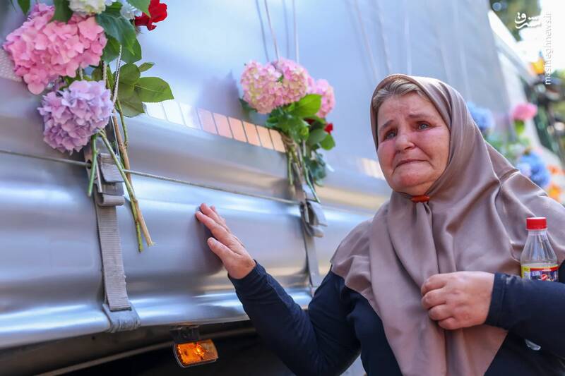 زنی بر روی کامیونی که 30 تابوت بقایای قربانیان قتل عام سربرنیتسا در سال 1995 شناسایی شده گل می‌گذارد./ ویسوکو _ بوسنی