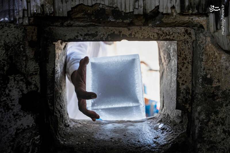 یک کارگر یک قطعه یخ را از از کارخانه یخ برمیدارد./ بصره _ عراق