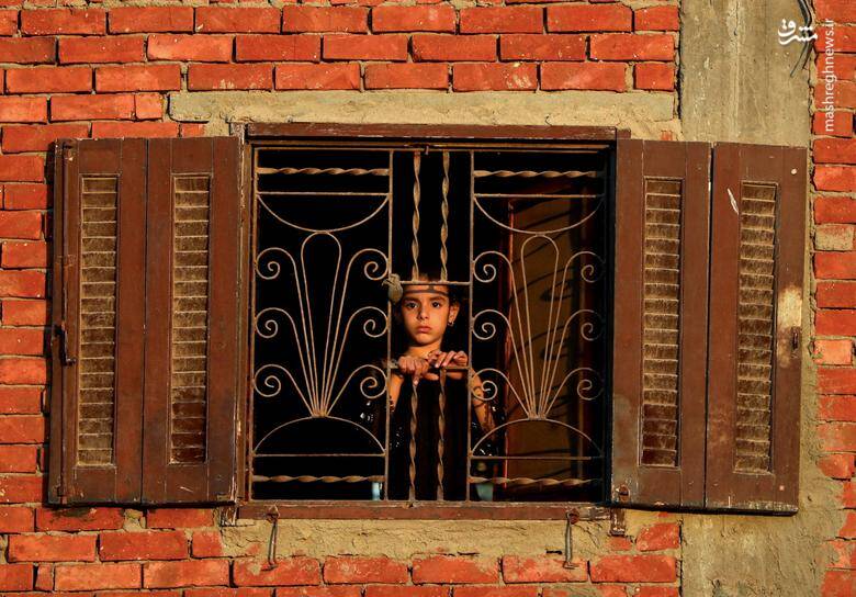 دختر بچه‌ای از پنجره اتاقش بیرون را نگاه می‌کند. / استان الشرقیه در شمال قاهره _ مصر