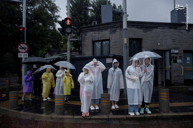 مردم در یک منطقه توریستی در هنگام بارش باران شدید در پکن 