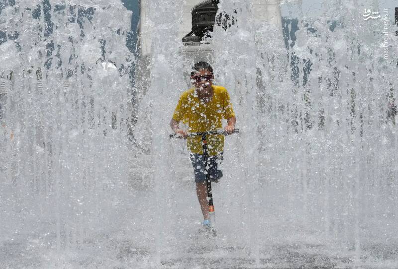 اسکوتر سواری یک پسر بچه و عبور از میان فواره‌های آب برای فرار از گرما در سئول _ کره جنوبی