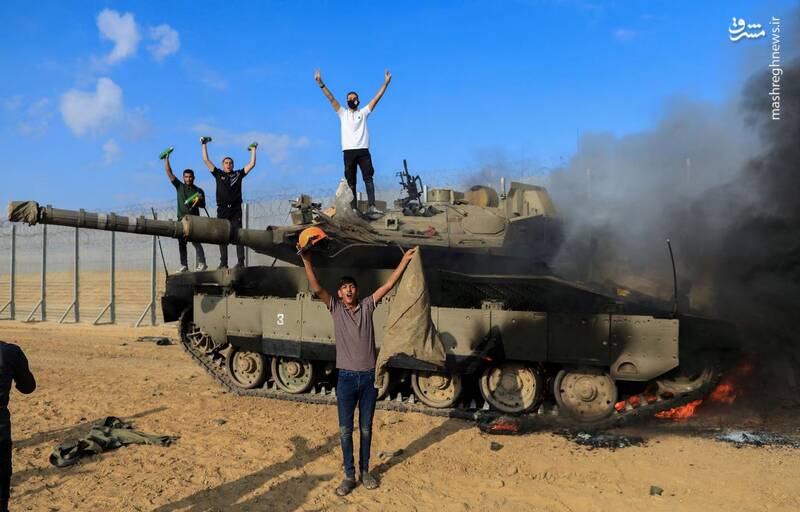 شادی فلسطینی‌ها در کنار تانک مهدم شده اسرائیلی توسط نیروهای مقاومت در مرز اسرائیل و غزه