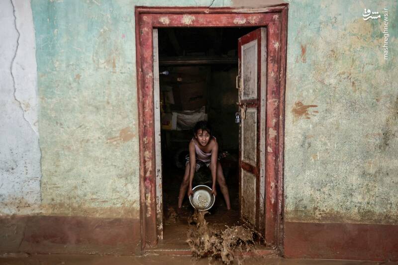 یک دختر بچه نپالی مشغول خروج سیلاب با یک سطل از خانهاش است یک دختر بچه نپالی مشغول خروج سیلاب با یک سطل از خانهاش است