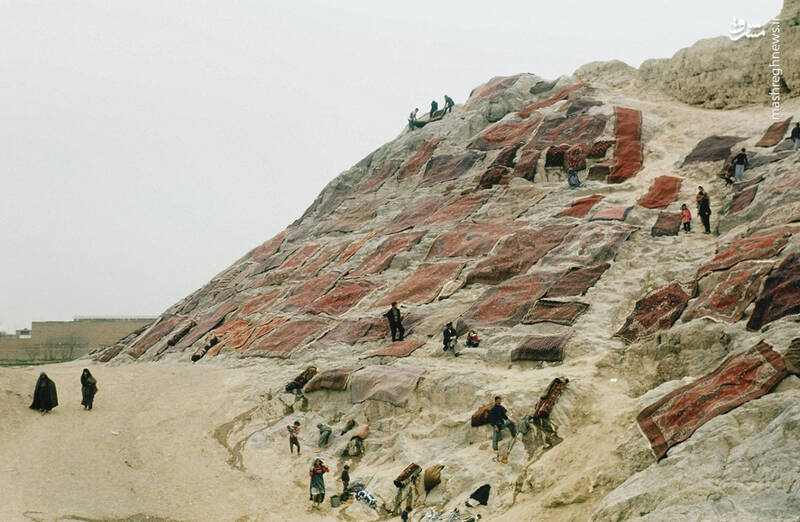 تصاویری از خشک کردن فرشهای ایرانی بر روی تپهٔ سنگی چشمهعلی ۶۴ سال پیش