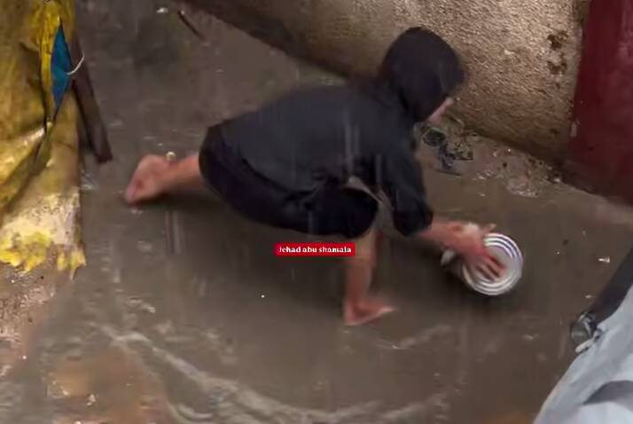  تلاش کودک فلسطینی برای تخلیه آب باران از چادر در غزه